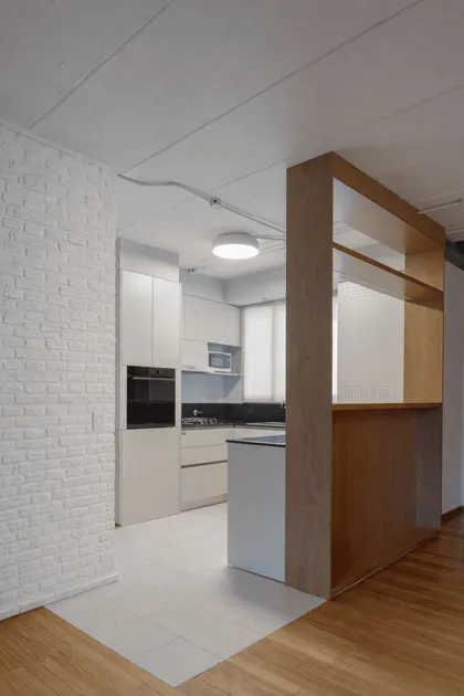 Cocina moderna integrada con isla, pared de ladrillo blanco y madera — proyecto Reforma 11 de septiembre, por Estudio YME, en Núñez